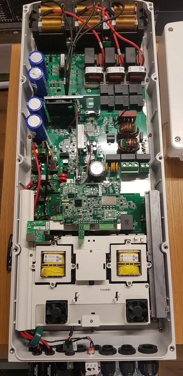 Inversor solar aberto em bancada mostrando placas eletrônicas, capacitores e relés