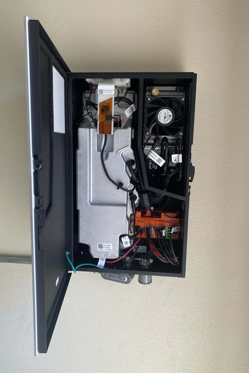 Inversor solar residencial aberto mostrando placas de potência, cabos e ventilação interna