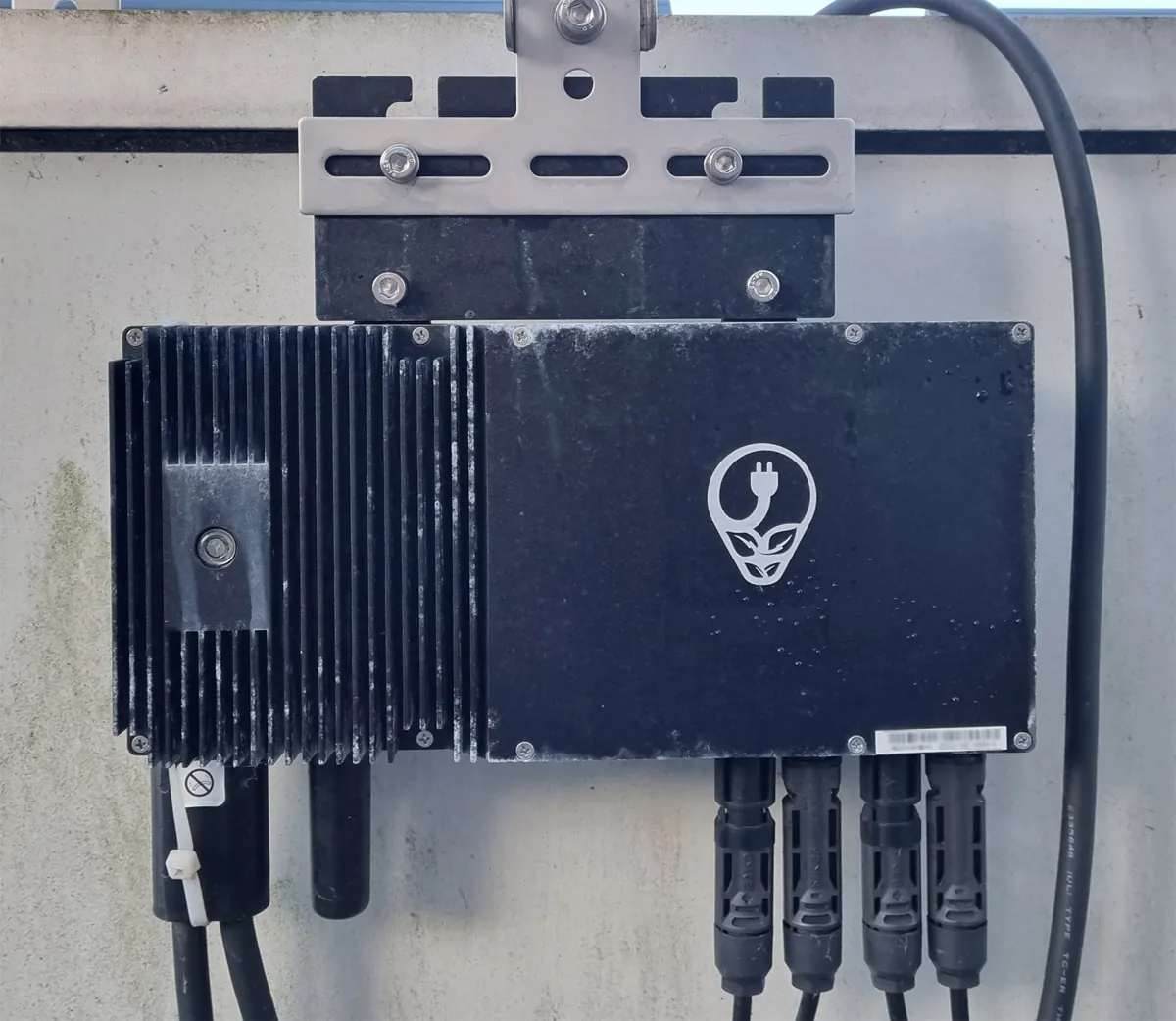Microinversor solar instalado sob a estrutura dos módulos, com cabos e conectores